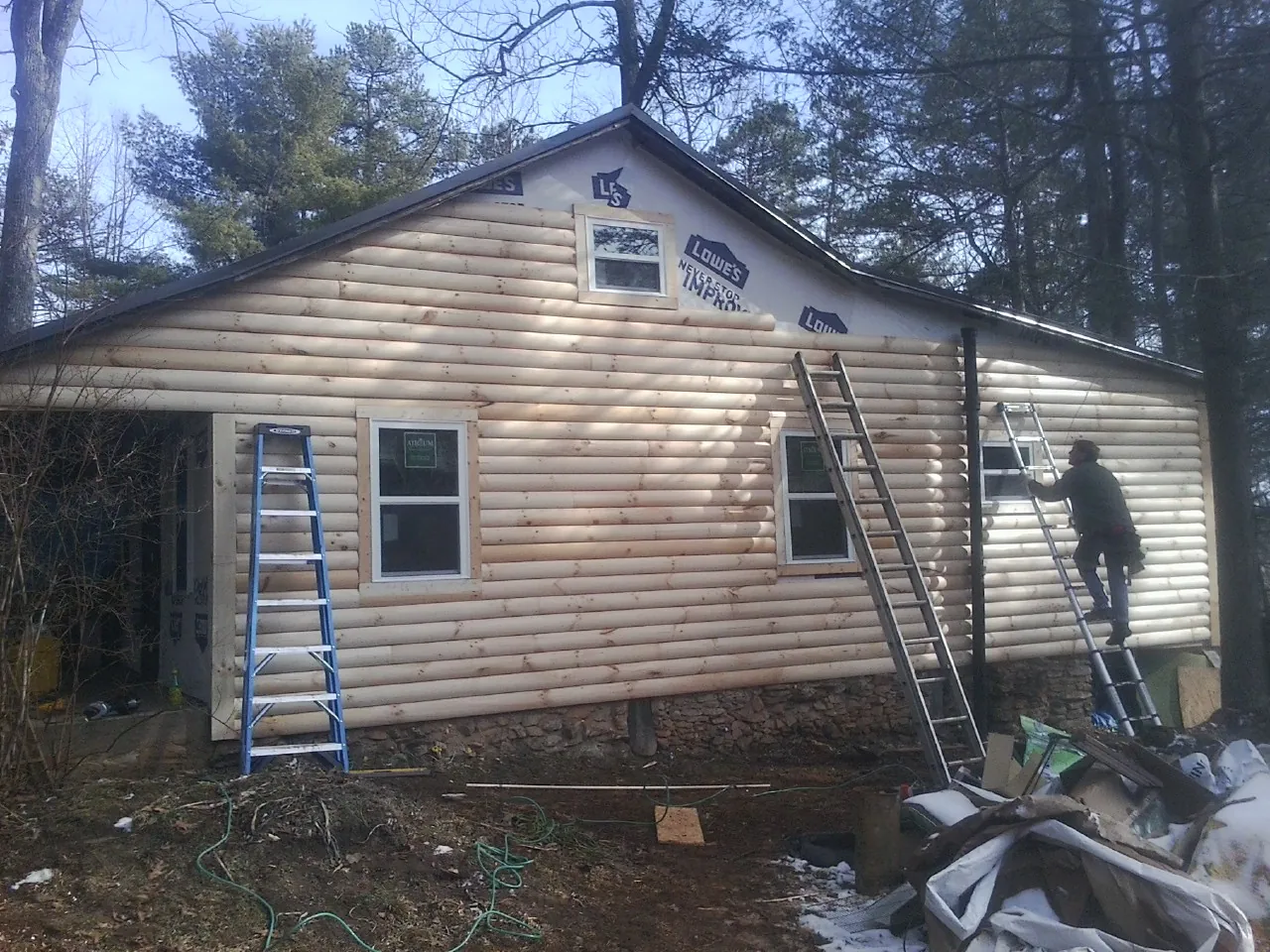 Ladders set against fresh log siding during an exterior remodel in Aspers