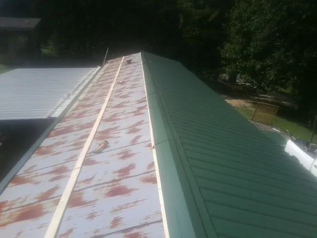 Old rusted panels beside newly installed green metal roofing — Wind Damage Roof Repair by Roofing Brothers in Aspers