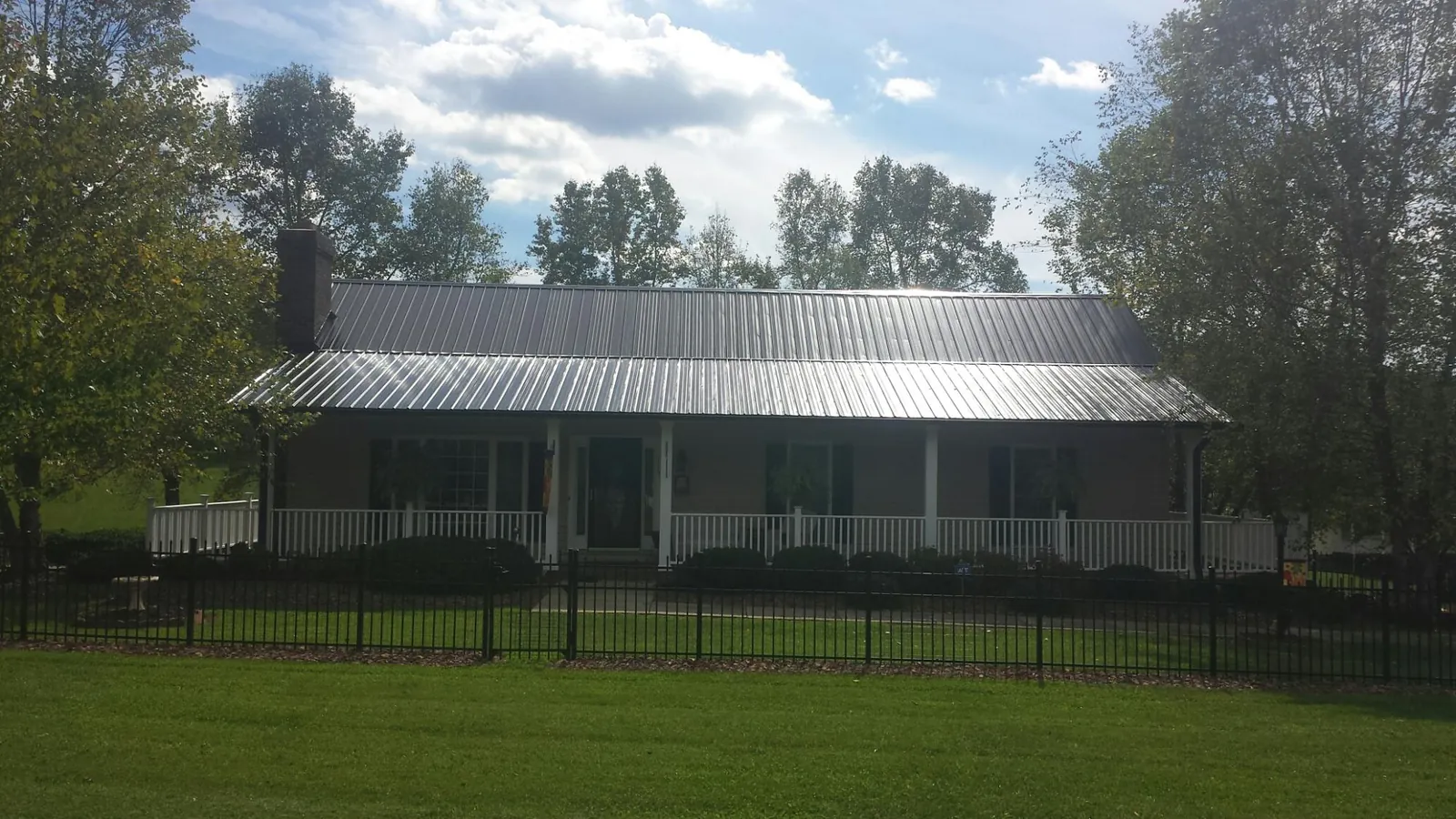 Gray metal roof on a brick ranch with a full width front porch — Gutter Guard Installation work by our crew in Aspers